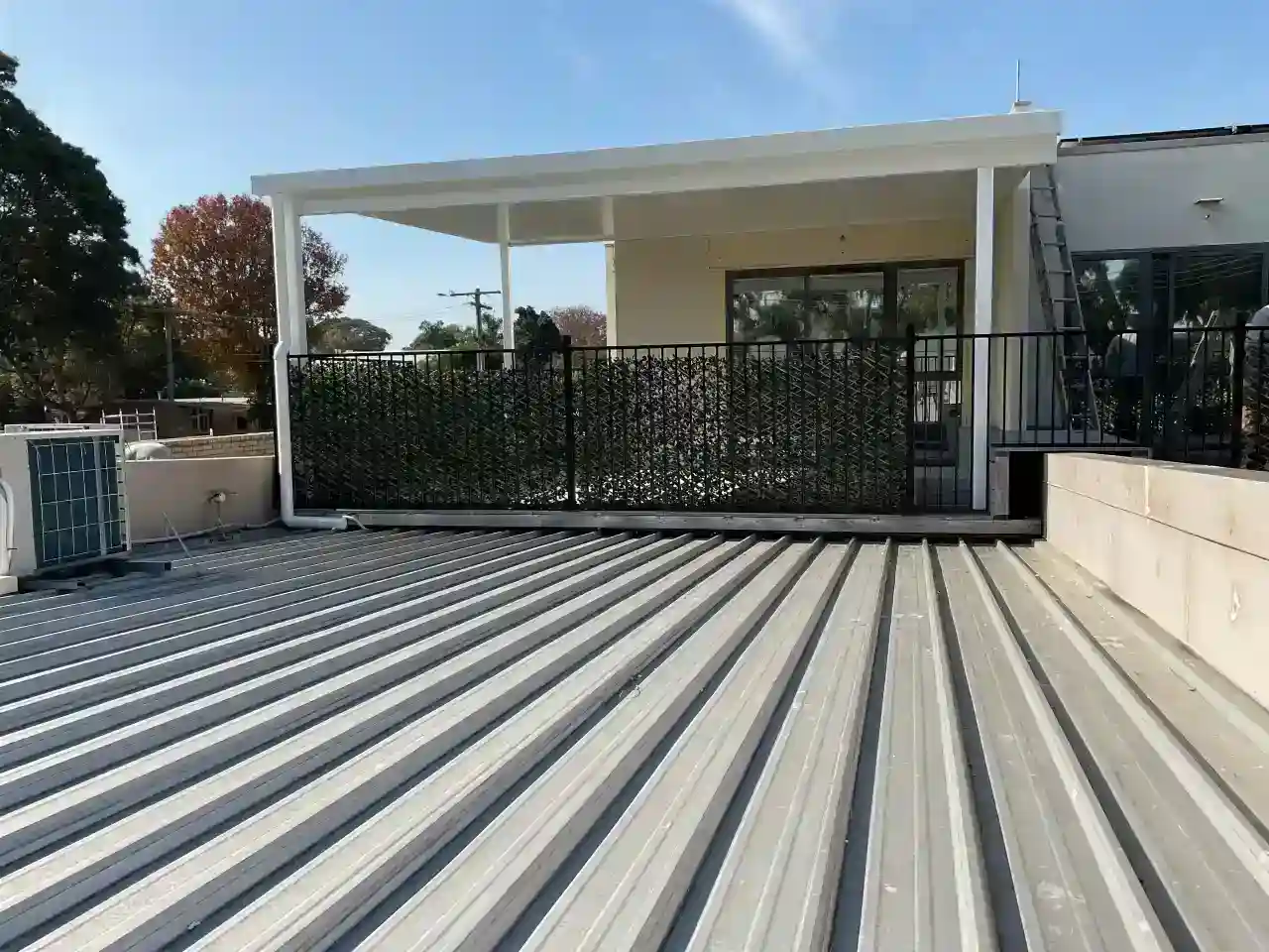 Balcony patio measuring 5.8m by 4.9m on the second storey of an office complex Featuring 55mm insulated roofing panels, 4 down lights