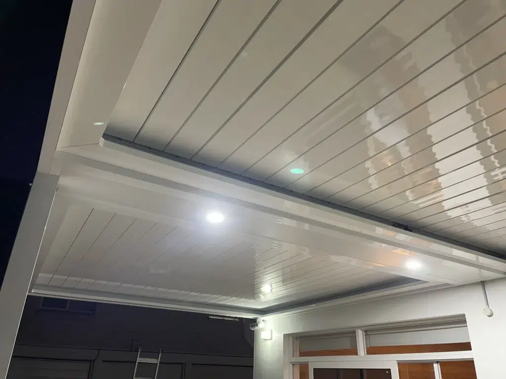 Night-time exterior view of illuminated louvred patio attached to double-storey home, Ascot Queensland