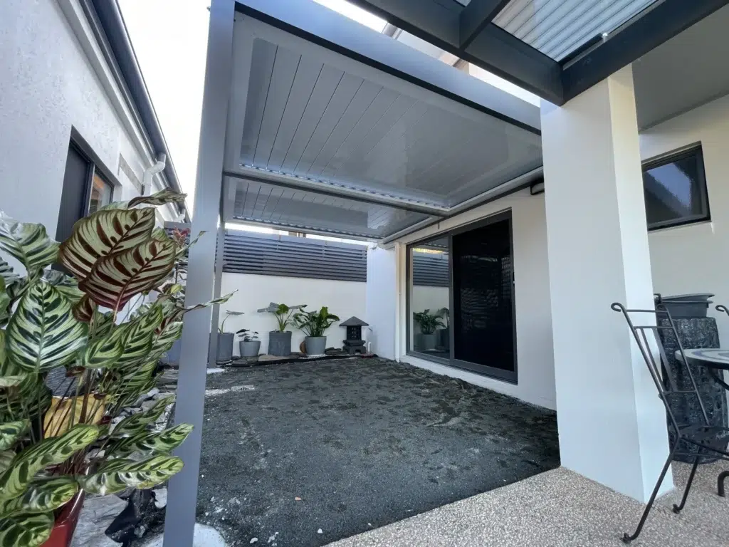 Interior view of louvred patio with open louvres, sliding door and potted plants, Pelican Waters Queensland