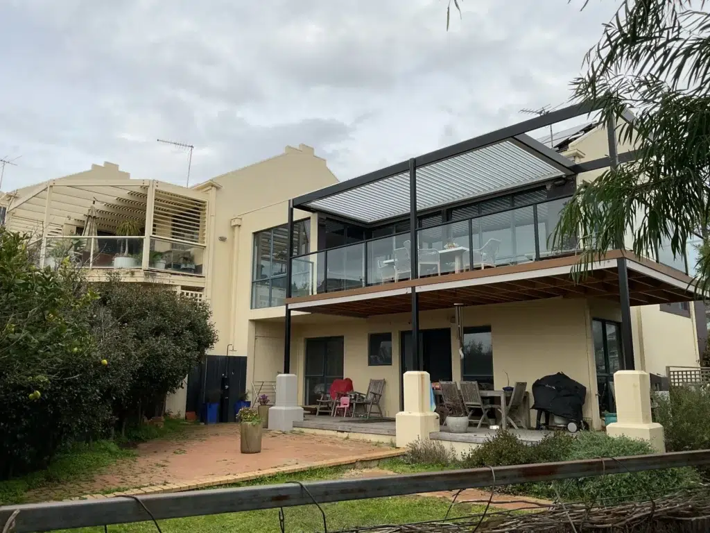 Full rear exterior view of two-storey home with grey-framed louvred pergola on upper balcony, Frankston Victoria