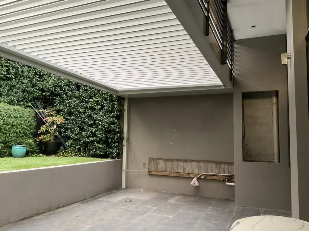 White louvred pergola with open louvres beside formal hedged garden with stone paving, Glen Iris Victoria