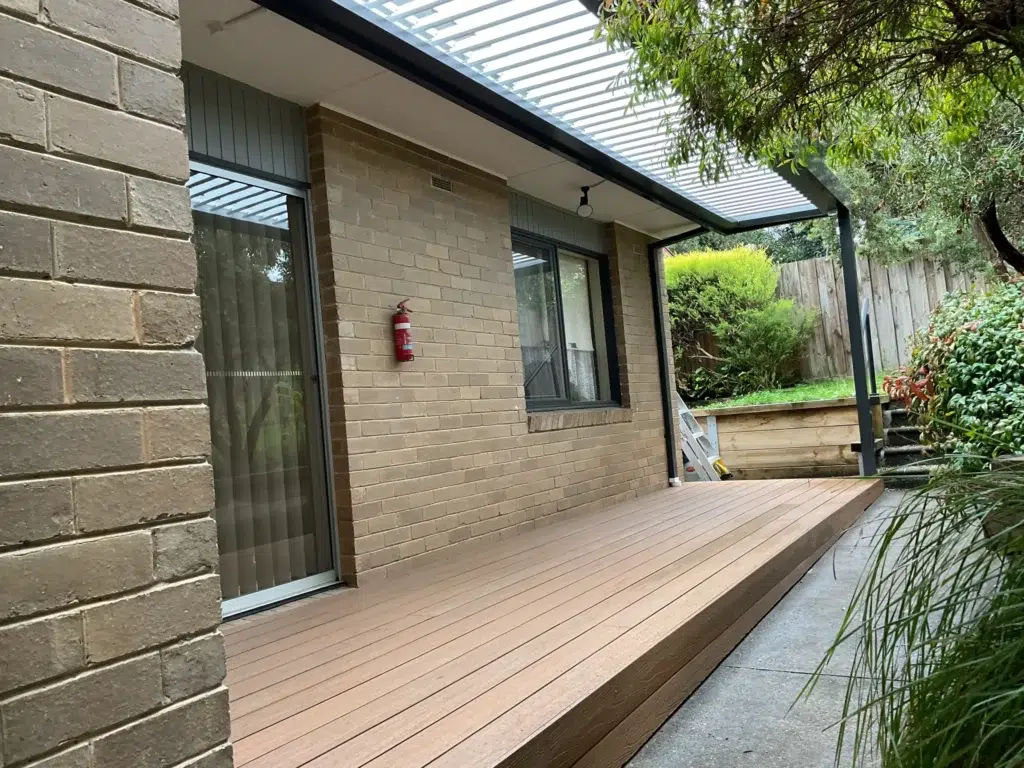 Louvred roof verandah with open louvres over new timber deck attached to brick home with garden, Victoria