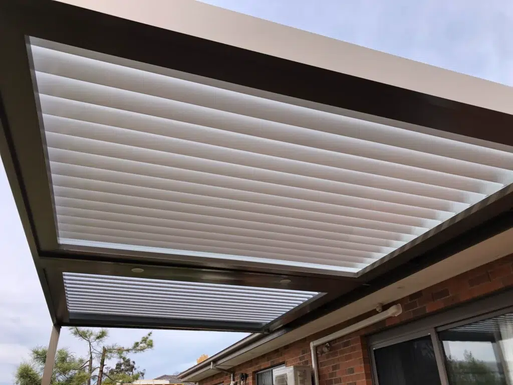 Interior view of louvred verandah timber deck with open louvre panels and garden greenery, Glen Waverley Victoria